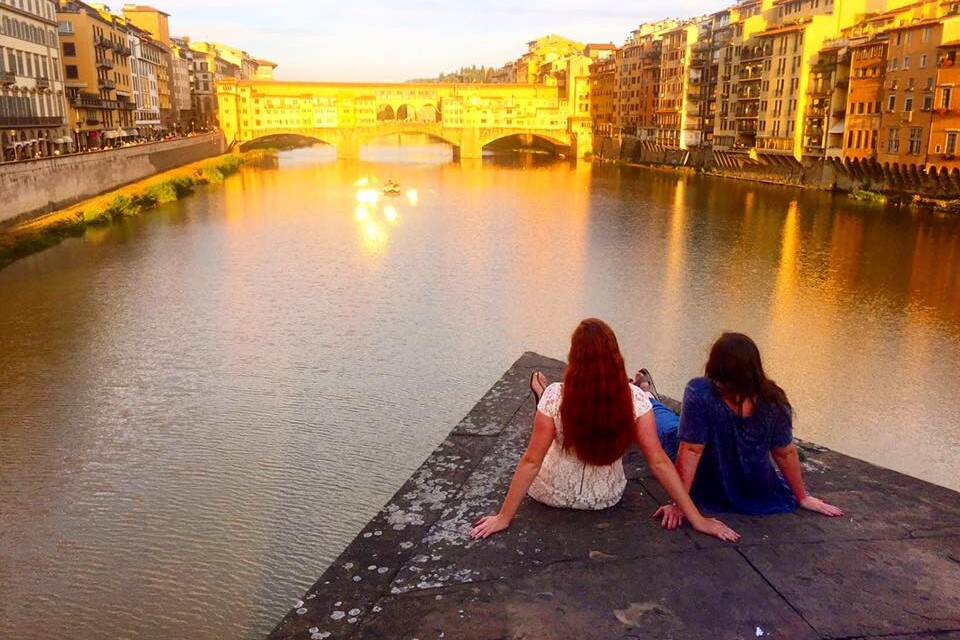 Two girls sitting on dock overlooking canal