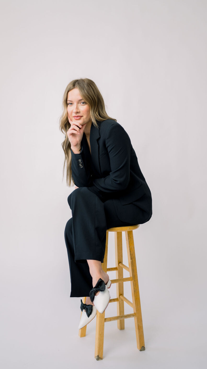 Young women sitting on a stool in front of a white background